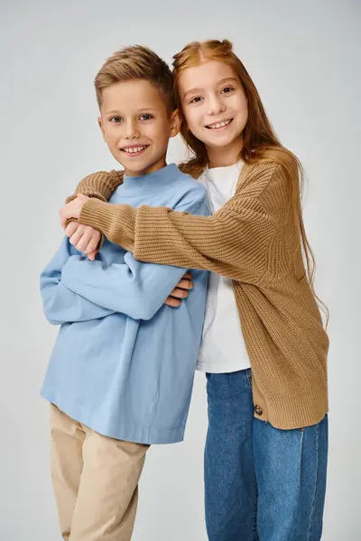 Vertical shot of jolly little friends in stylish attires hugging and smiling at camera, fashion — Stock Photo