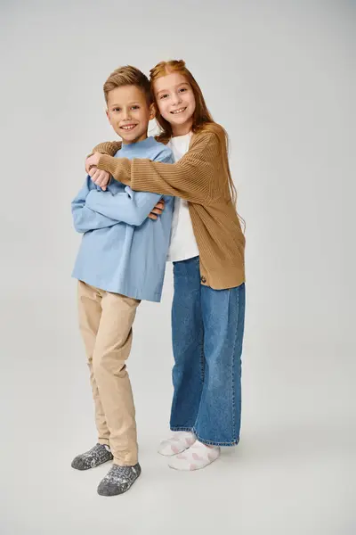 Joyous little friends in casual stylish clothes hugging and smiling at camera, fashion concept — Stock Photo