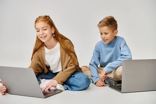 Fröhlicher kleiner Junge schaut auf Laptop seiner Freundin und lächelt fröhlich, Modekonzept — Stockfoto