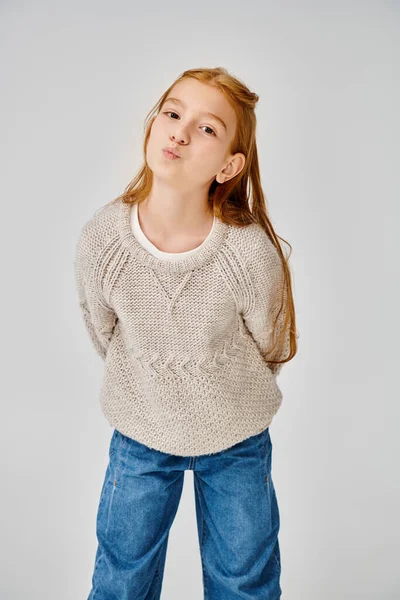 Jolly preadolescent girl in knitted trendy sweater looking at camera with pouted lips, fashion — Stock Photo