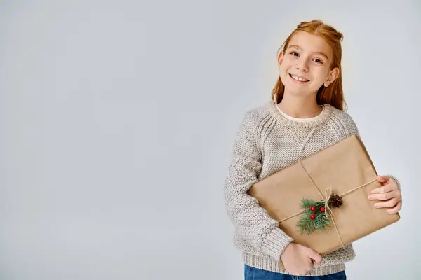 Мила дівчина-підліток в в'язаному теплому светрі тримає подарунок в руках і радісно посміхається — стокове фото