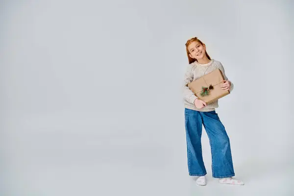 Joyful preteen girl in stylish casual outfit holding present and smiling at camera, fashion, concept — Stock Photo