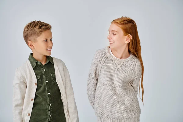 Jolly preadolescent boy and girl in stylish casual attires smiling happily at each other, fashion — Stock Photo