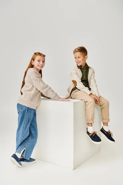 Cheerful little boy in cardigan smiling at preteen red haired girl that looking at camera, fashion — Stock Photo