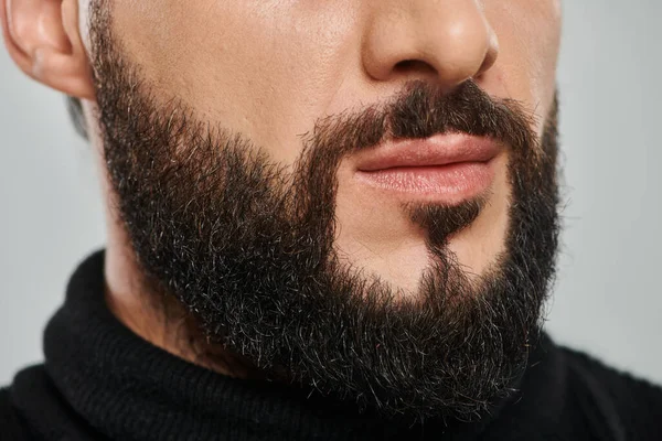 Cropped shot of confident bearded arabic man in black turtleneck posing on grey background — Stock Photo