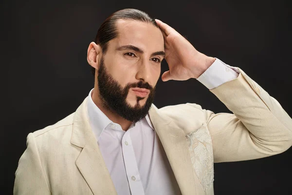 Eleganter und bärtiger arabischer Mann in weißem Hemd und Blazer, der vor schwarzem Hintergrund wegschaut — Stockfoto
