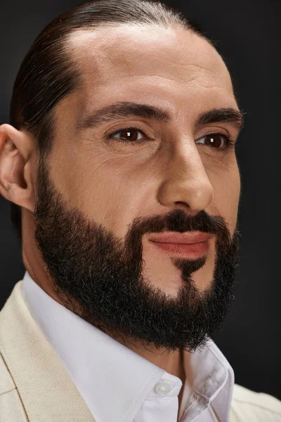 Primer plano retrato de barbudo y guapo hombre árabe en traje elegante posando sobre fondo negro - foto de stock