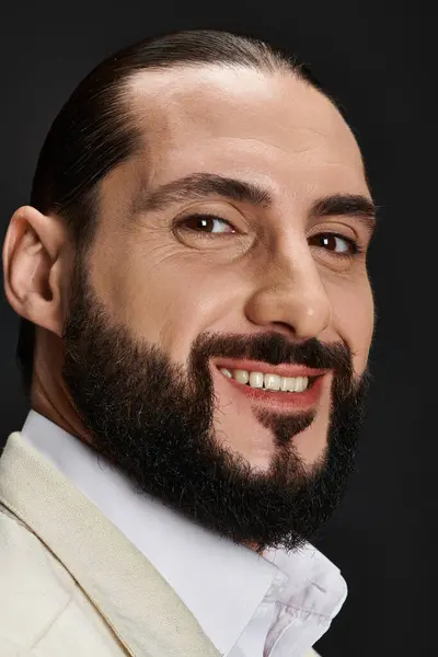 Close up portrait of bearded and joyful arabic man in elegant attire posing on black backdrop — Stock Photo