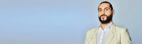 Модный и бородатый мужчина в белой рубашке и блейзере позирует на сером фоне, элегантный наряд — стоковое фото