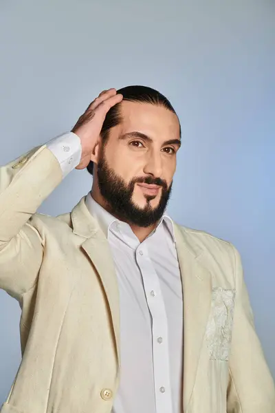Модный бородатый мужчина в белой рубашке и блейзере позирует на сером фоне, элегантный наряд — стоковое фото