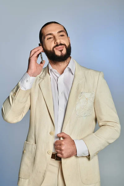 Happy bearded arabic man in white formal wear talking on smartphone on grey background, phone call — Stock Photo