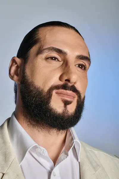 Retrato de hombre árabe guapo y barbudo en traje elegante blanco sobre fondo gris, confiado - foto de stock