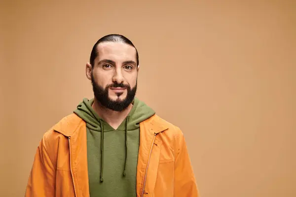 Portrait of handsome and bearded arabic man in casual attire looking at camera on beige backdrop — Stock Photo