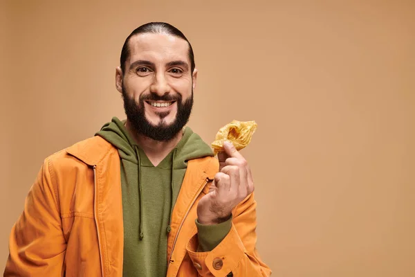 Homme heureux tenant du miel baklava et regardant la caméra sur beige, dessert traditionnel du Moyen-Orient — Photo de stock