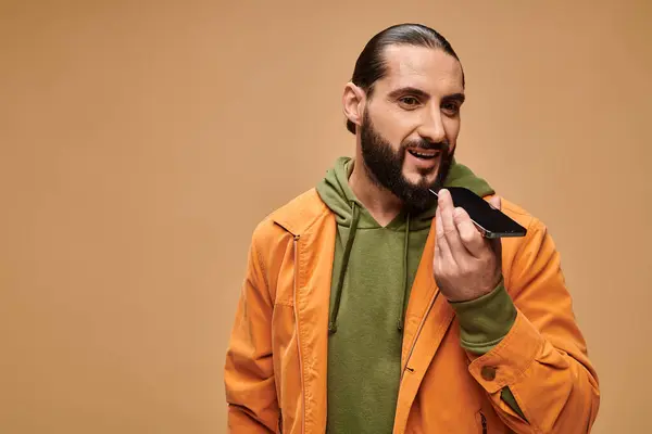 Feliz homem do Oriente Médio com barba enviando mensagem de voz em fundo bege, smartphone — Fotografia de Stock