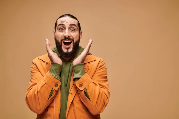 Surprised middle eastern man with beard and open mouth gesturing on beige background, wow — Stock Photo
