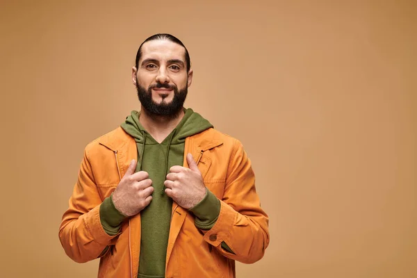 Pleased middle eastern man with beard standing in casual attire on beige backdrop, looking at camera — Stock Photo