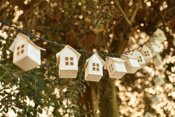 Eco-friendly garland made of wooden houses on green tree with fresh foliage inside of greenhouse — Stock Photo