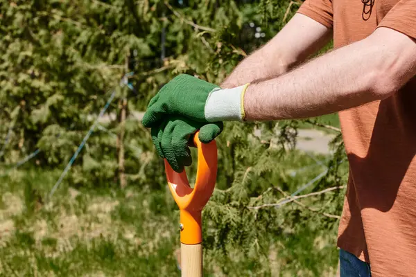 Cropped view of farmer in gloves holding shovel while standing outdoors, plant care — Stock Photo
