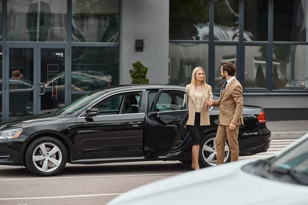 Coppia d'affari in elegante abbigliamento formale che si tiene per mano e si guarda vicino auto sulla strada — Foto stock