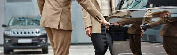 Partial view of man in elegant formal wear opening door of luxury car near businesswoman, banner — Stock Photo