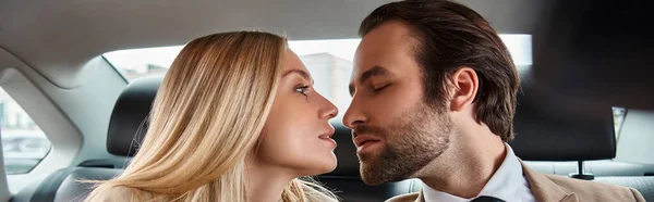 Élégant homme d'affaires et jolie femme blonde assise face à face dans une voiture de luxe, bannière — Photo de stock