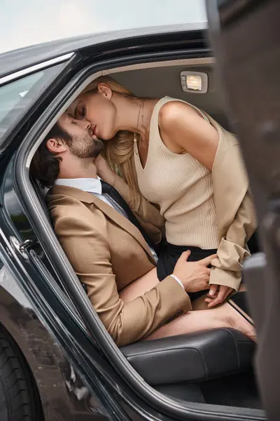 Couple d'affaires réussi dans l'élégante tenue formelle embrassant et embrassant dans la voiture de luxe, histoire d'amour — Photo de stock