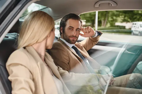Handsome businessman looking at blonde female colleague while seducing her in car, attraction — Stock Photo