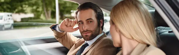 Stylish businessman looking at blonde female colleague while seducing her in luxury car, banner — Stock Photo