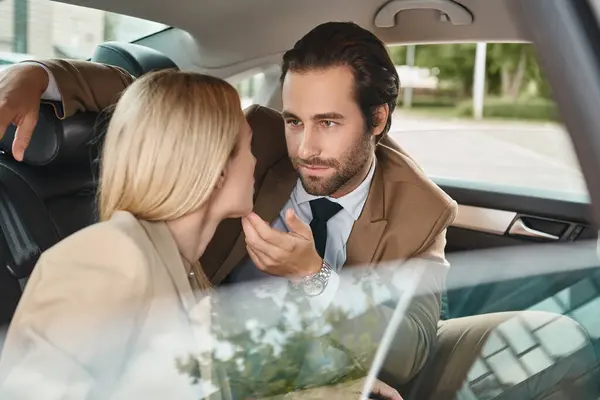 Homme élégant en tenue formelle toucher menton de femme d'affaires blonde tout en voyageant en voiture, séduction — Photo de stock
