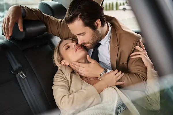 Homme élégant en costume embrassant blonde femme d'affaires passionnée tout en voyageant en voiture, séduction — Photo de stock