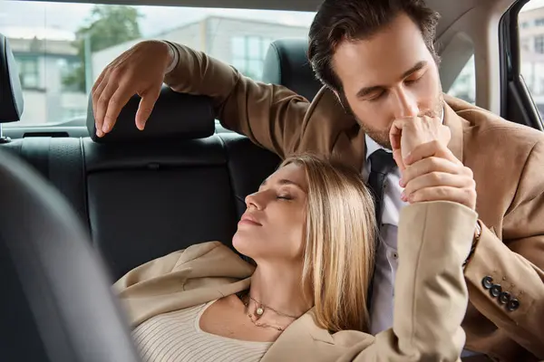 Homme d'affaires en costume baisers main de blonde femme passionnée tout en voyageant en voiture, séduction — Photo de stock