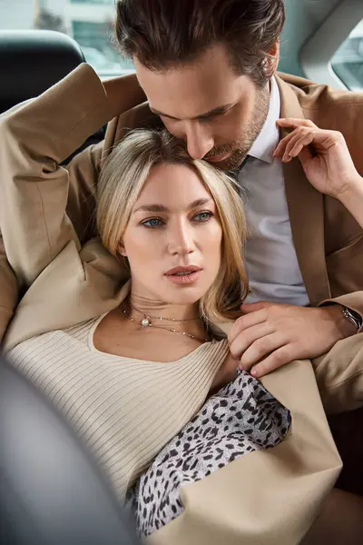 Handsome man in suit embracing and seducing passionate blonde woman while traveling in car, romance — Stock Photo