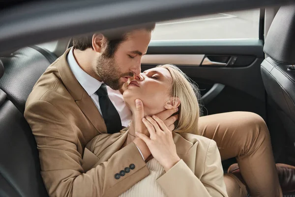Coppia d'affari elegante e di successo baciare con gli occhi chiusi durante il viaggio in auto, romanticismo — Foto stock