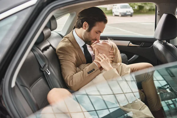 Élégant et sensuel couple d'affaires baisers avec les yeux fermés tout en voyageant en voiture, romance — Photo de stock