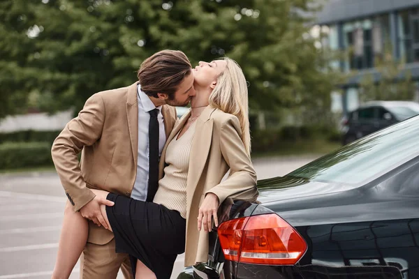 Homme élégant en tenue formelle séduire élégante femme d'affaires blonde près de la voiture sur la rue, histoire d'amour — Photo de stock