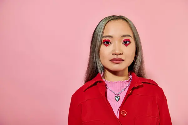 Porträt einer jungen Asiatin mit herzförmigem Augen-Make-up und gefärbten Haaren, die vor rosa Hintergrund posiert — Stockfoto