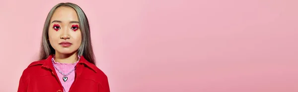 Retrato de jovem mulher asiática com coração em forma de maquiagem olho e cabelo tingido posando em rosa, banner — Fotografia de Stock