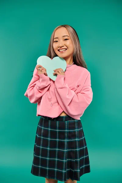 Happy Valentines day, joyful asian woman holding heart shaped carton on turquoise background — Stock Photo