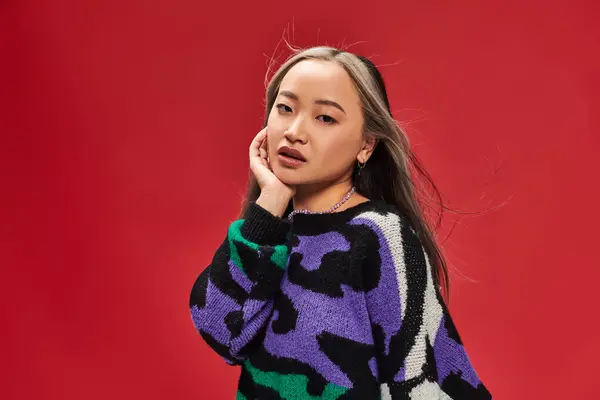 Schöne junge asiatische Frau mit gefärbten Haaren im Pullover mit Animal Print posiert mit händennahem Gesicht — Stockfoto