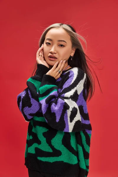 Junge hübsche asiatische Frau mit gefärbten Haaren im Pullover mit Animal Print posiert mit händennahem Gesicht — Stockfoto