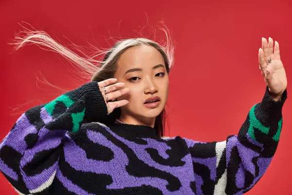 Ветер дует в лицо красивой молодой азиатской женщины с окрашенными волосами в свитере с отпечатками животных — стоковое фото