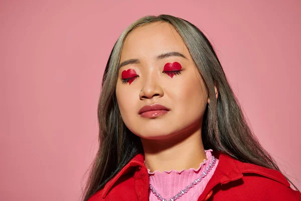 Valentines day concept, young asian woman with heart shaped eye makeup and closed eyes on pink — Stock Photo