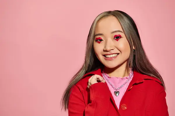 Valentinstag Konzept, fröhliche asiatische Frau mit herzförmigen Augen Make-up lächelnd auf rosa Hintergrund — Stockfoto