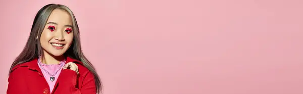 San Valentino banner, allegra donna asiatica con trucco agli occhi a forma di cuore in posa su sfondo rosa — Foto stock