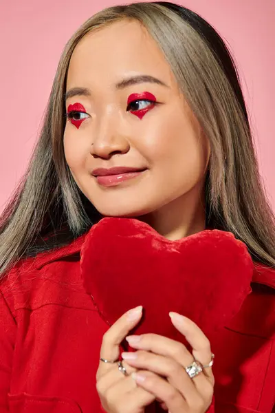 Valentines day, pretty asian woman with vibrant eye makeup holding red heart on pink backdrop — Stock Photo