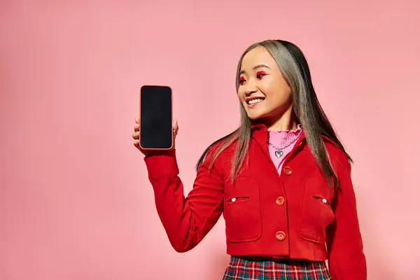 Happy asian woman with red Valentines day makeup showing smartphone with blank screen on pink — Stock Photo