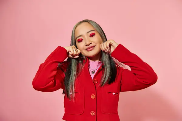 Portrait de asiatique jeune fille avec coeur forme oeil maquillage montrant pleurer geste sur fond rose — Photo de stock