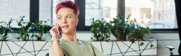 Stylish queer manager talking on mobile phone and looking away in modern office, horizontal banner — Stock Photo