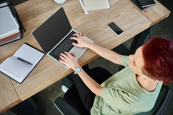 Top view of queer person typing on laptop with blank screen near smartphone and notebook in office — Stock Photo